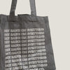 Gray tote bag with 'Hot Sauce on Everything' text in a store setting with hot sauce bottles.
